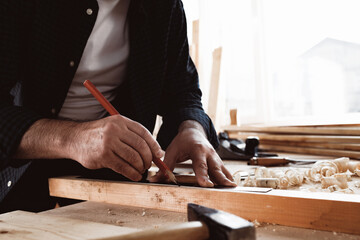 Carpenter makes pencil marks on a wood plank