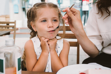 Young mom eating cake with smiling kid on the street