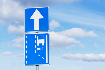 Bus only lane road sign. One way road sign. Arrow isolated on blue sky. Information blue sign.