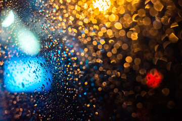 Wet the window with the background of the autumn night city. defocus. bright lights, bokeh.