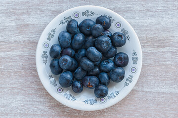 Blueberries on a round plate on a wooden table. Top view.