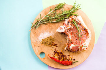 Uncooked pork steak on the wooden board, salt, spices and rosemary