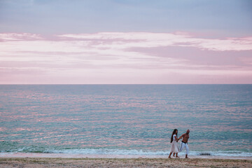 Happy couple walk barefoot on the beach