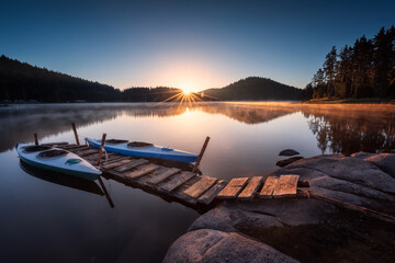 Lake sunrise. Beautiful sunrise view of mountain lake with  wooden bridge and canoes.