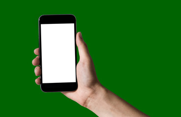 Hand holding white mobile phone with blank white screen in green background.