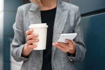 Closeup shoot of woman's hands with the phone and cup of coffee at the business center outdoors