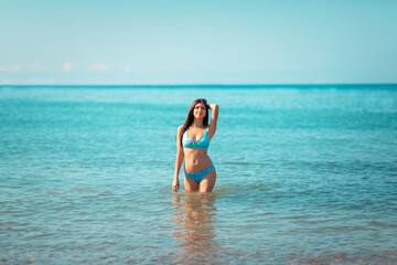 Summer. A young beautiful woman poses standing at the ocean. The concept of summer holidays
