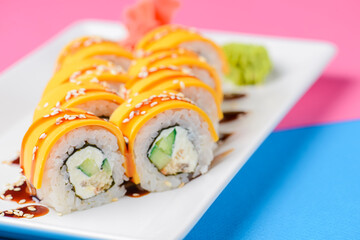 Sushi large set served on a white plate over pink background. Traditional Asian Japanese cuisine concept.