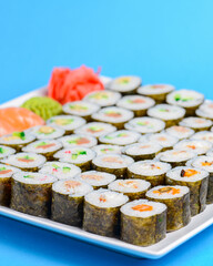 Sushi large set served on a white plate over blue background. Traditional Asian Japanese cuisine concept.