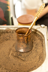 Turkish coffee prepared on hot sand for an unique taste and aroma. Traditional oriental beverage in copper cezve