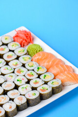 Sushi large set served on a white plate over blue background. Traditional Asian Japanese cuisine concept.
