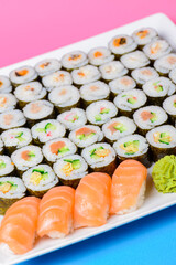 Sushi large set served on a white plate over pink background. Traditional Asian Japanese cuisine concept.