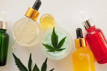 Marijuana leaves, cbd oil, cosmetic cream. Cannabis extract in cosmetology. Flat lay, powder background. Home relaxation, spa recreation, pastime therapy.