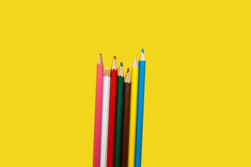 colored wooden pencils on a yellow background