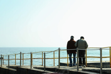 Two men standing on pier against sea