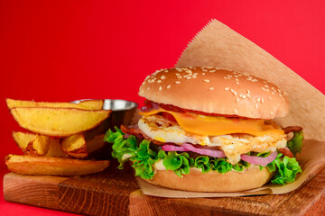 Bacon and beef patty burger with red onions and cheese over red background. Fast food, junk food concept.