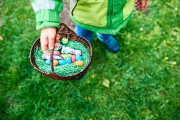 Kind hält Korb mit Ostereiern in der Hand die versteckt waren,