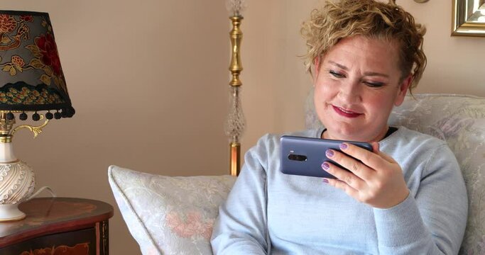 Portrait Of A Middle Aged Blond Woman With Cell Phone Looking Shocked