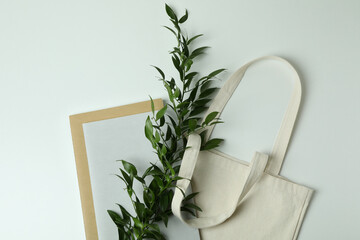 Eco bag, copybooks and twig on white background