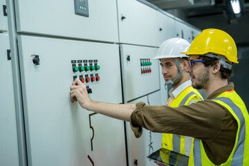 Maintenance engineers inspect relay protection system in control room of a modern thermal power plant at large industry factory.