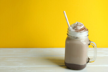 Chocolate milkshake on wooden table against yellow background