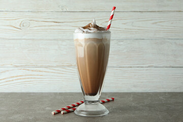 Glass of chocolate milkshake and straws on gray table
