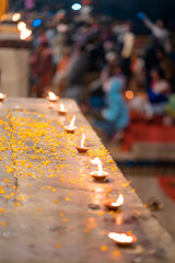 Hindu Diwali festival. Burning candles standing in a row on a table sprinkled with flower petals. Blurred background. Top view, close-up