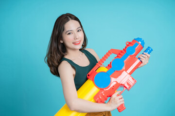 Asian woman holding water gun for Songkran festival in studio on blue background.