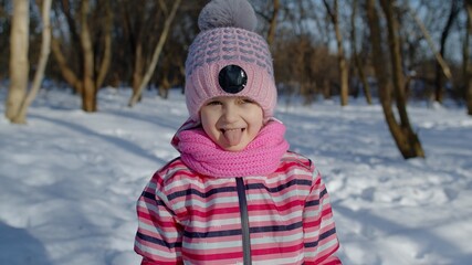 Smiling child kid looking at camera, showing tongue, fooling around, making faces in winter park