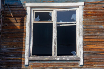 Broken window in a wooden frame in an old wooden house. An old abandoned house. Empty windows.