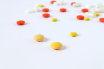 Yellow vitamins on the background of scattered ampoules and tablets on a light background, side view