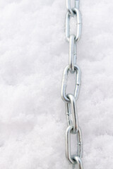 A metal chain lies on the snow in winter