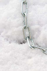 A metal chain lies on the snow in winter