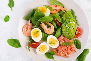 Ketogenic diet breakfast. Salt salmon salad with boiled shrimps, prawns, tomatoes, spinach, eggs and avocado. Keto, paleo lunch. Top view, overhead