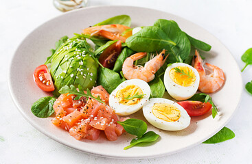 Ketogenic diet breakfast. Salt salmon salad with boiled shrimps, prawns, tomatoes, spinach, eggs and avocado. Keto, paleo lunch.