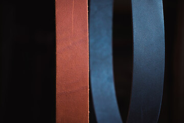 Blue and black leather straps on a black background close-up