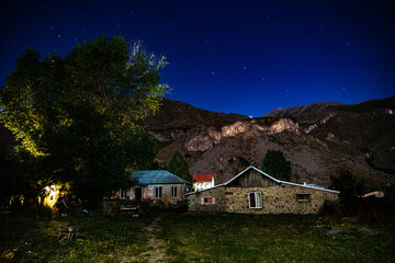 House and mountains with green grass, trees at night