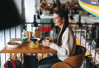 Attractive young brunette smiling woman in casual having brunch in the cafe, healthy food
