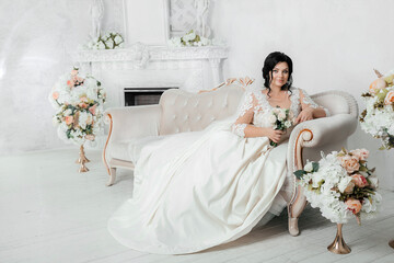 Beautiful sexy brunette bride plus size in a light photo studio. Wedding photo. Plus size model...