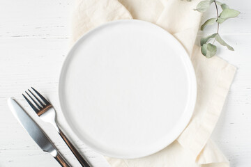 An empty plate and cutlery on a white wooden table. Top view. - Powered by Adobe