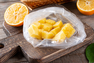 Frozen Lemon Juice cubes in the bag on a wooden table, frozen fruit