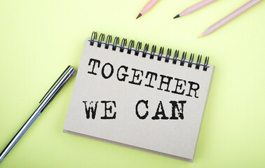 Together We Can text on the notebook with pen on yellow background