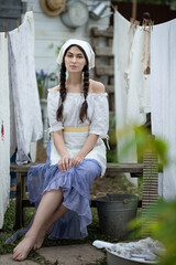 A woman in an apron sits among the washed laundry