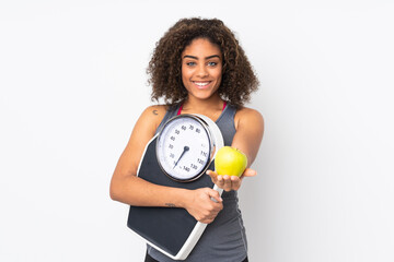 Young African American woman isolated on white background holding weighing machine and offering an...
