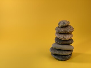Fototapeta na wymiar pebble stones form a pyramid on a yellow background