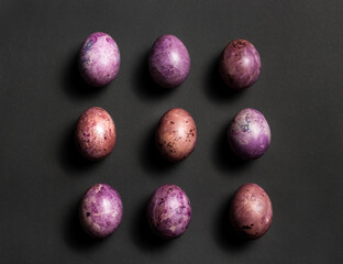 Colorful nine painted eggs on the black surface. Easter flat lay with copy space. Image for greetings and invitation cards.