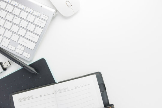 Flat lay, top view office table. Office supplies, keyboard, pen mouse, notebook, and flash drive on white office table background with copy space, workspace blank. Office table concept.