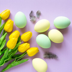 Fototapeta na wymiar Easter flat lay. Painted eggs with tulips and feathers on lilac background, top view