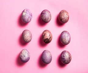 Colorful nine painted eggs on the pink surface. Easter flat lay with copy space. Image for greetings and invitation cards.