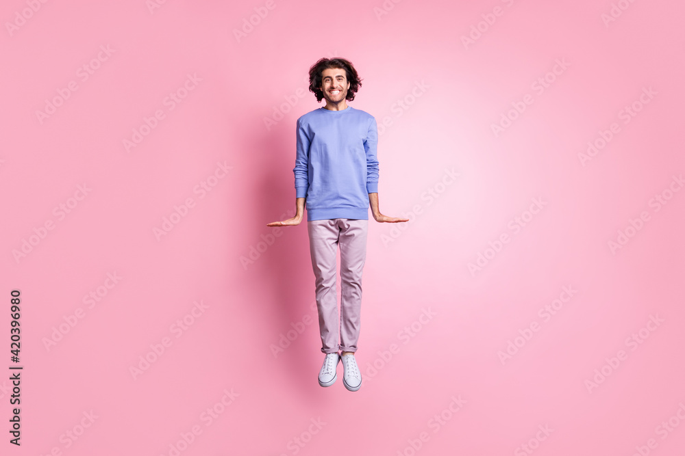 Wall mural Full size photo of young attractive smiling cheerful positive man fly jump wear purple trousers isolated on pink color background